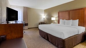 Une chambre d’hôtel avec un grand lit, un bureau doté d’un téléviseur à écran plat, une lampe et une table de chevet.