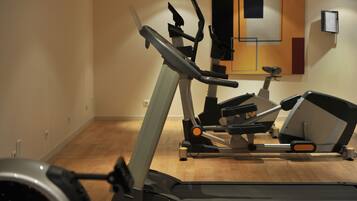 Un gimnasio con equipamiento de ejercicio, incluyendo cintas de correr y elípticas.