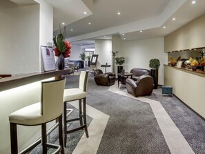 Un moderno vestíbulo con mostrador de recepción, zona de estar y plantas decorativas.