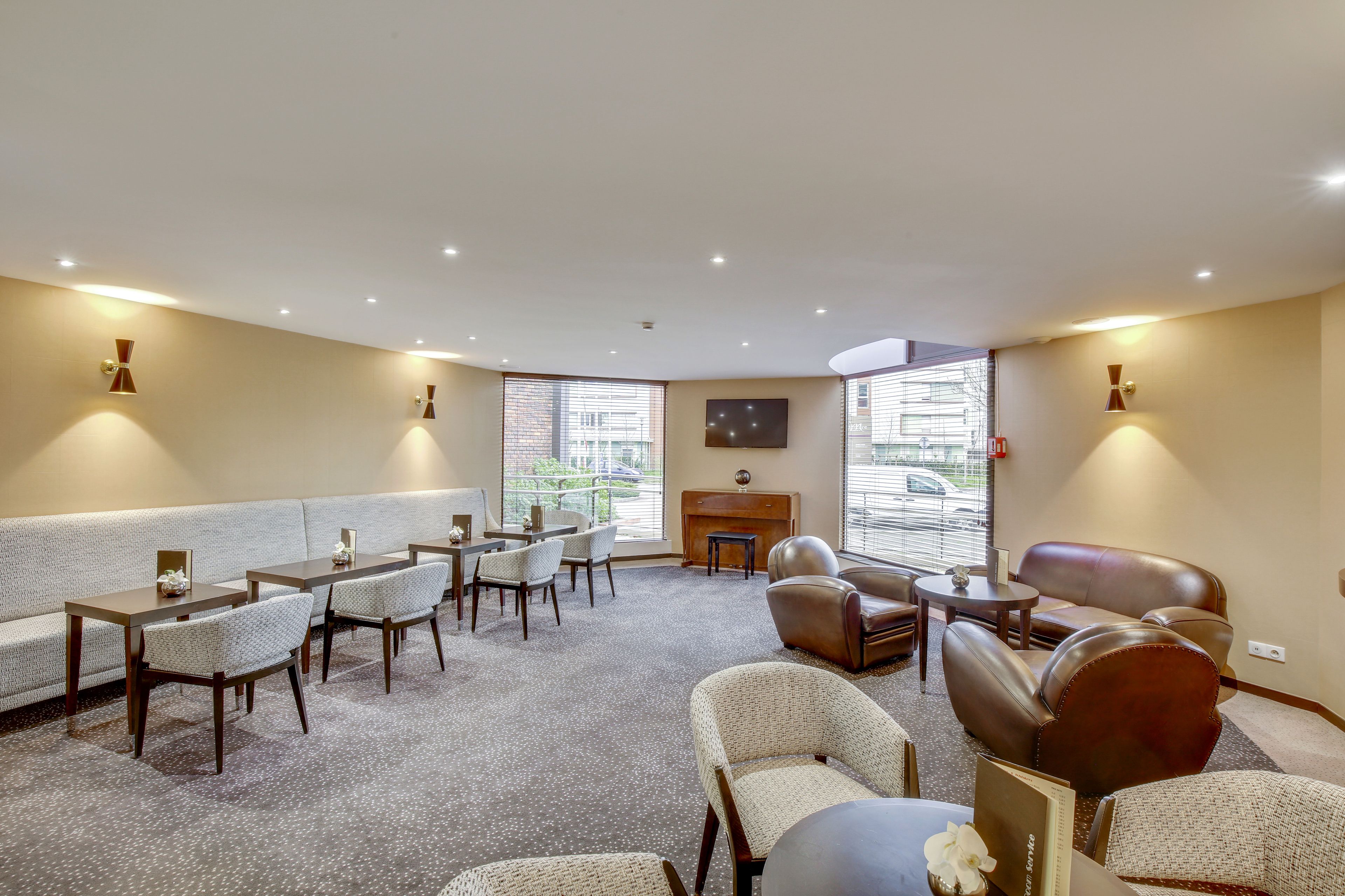 Een hotelkamer met een bank, stoelen, een eettafel en een open haard.