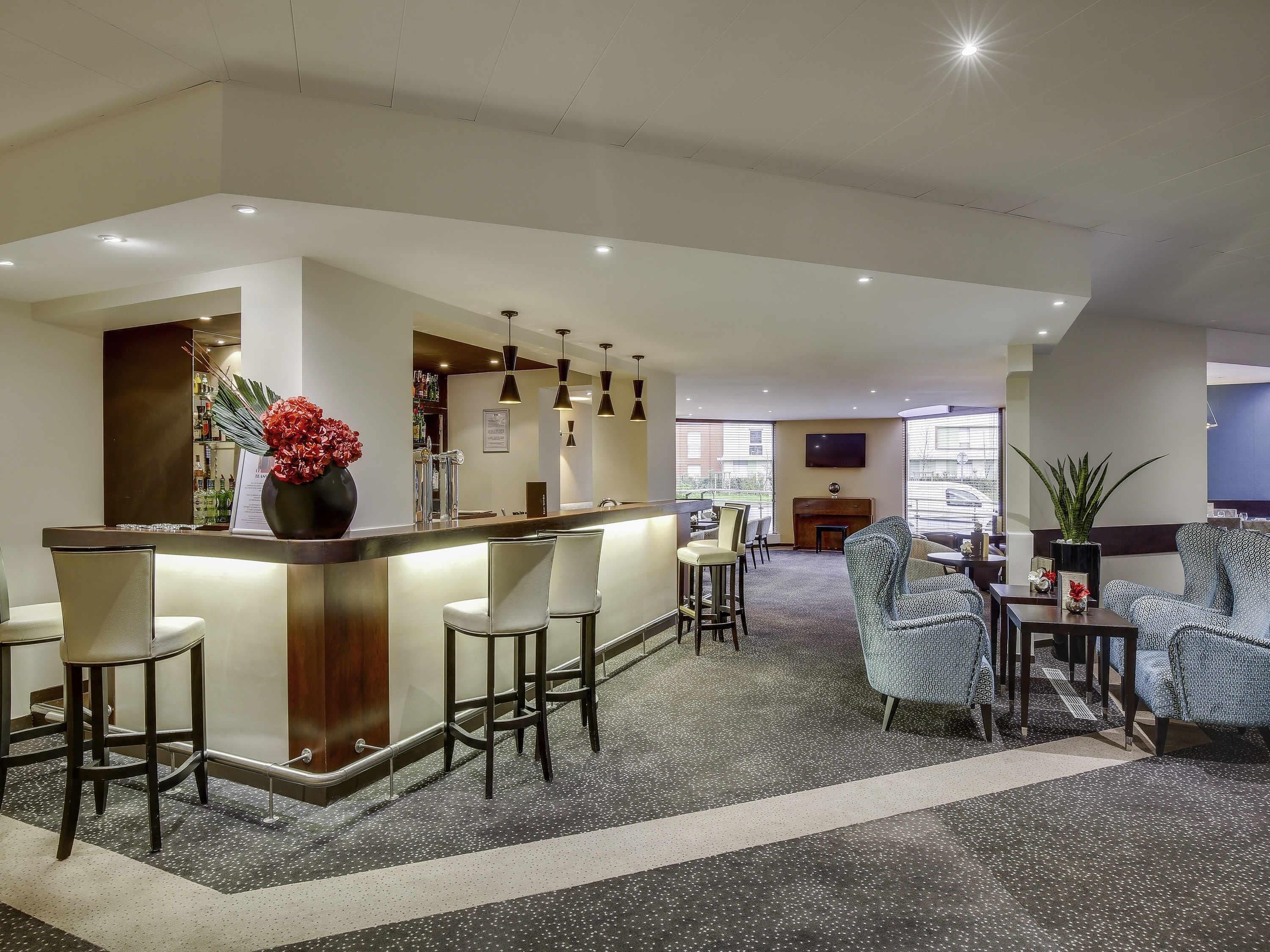 Een hotel lobby met een bar, zitplaatsen en een televisie.