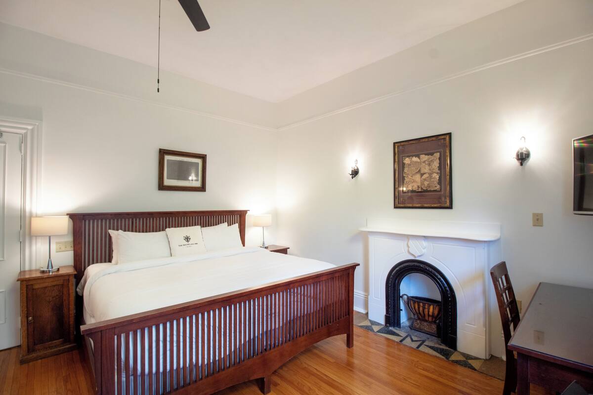 A bedroom with a wooden bed, a fireplace, and a dining table.
