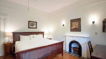 A bedroom with a wooden bed, a fireplace, and a dining table.