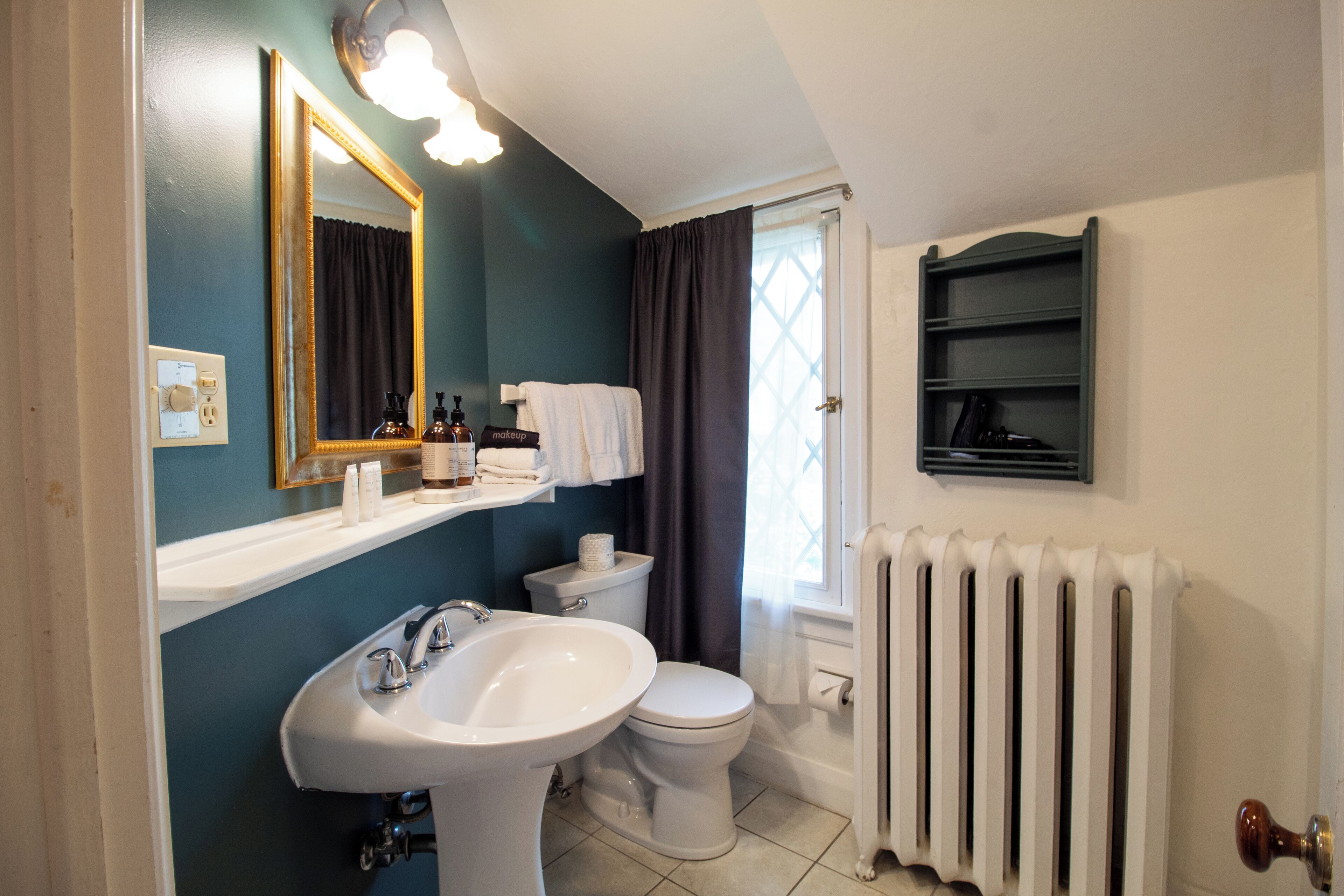 A bathroom with a white sink, a toilet, a mirror, and a radiator.