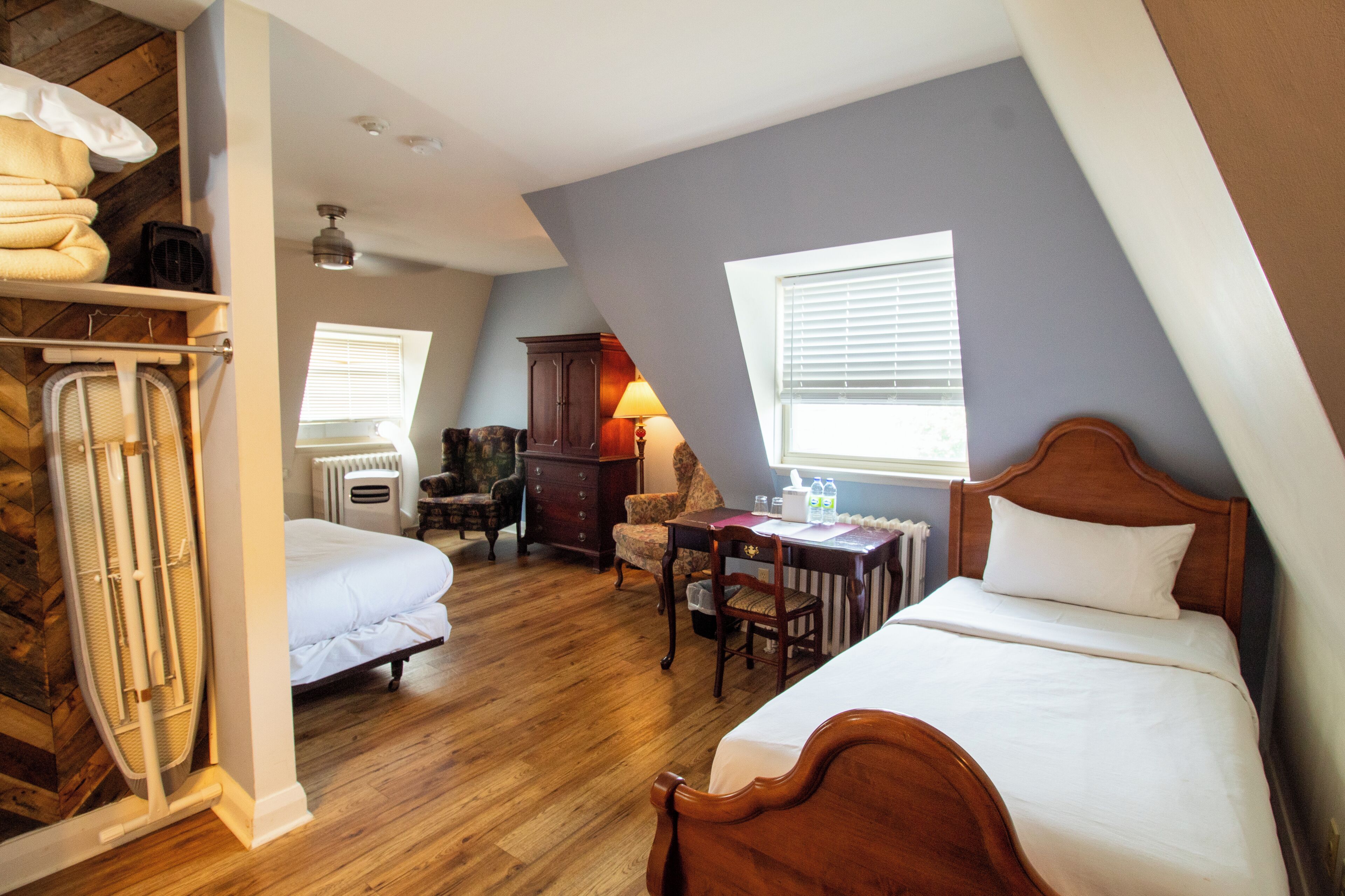 A bedroom with two beds, a desk, and a chair.