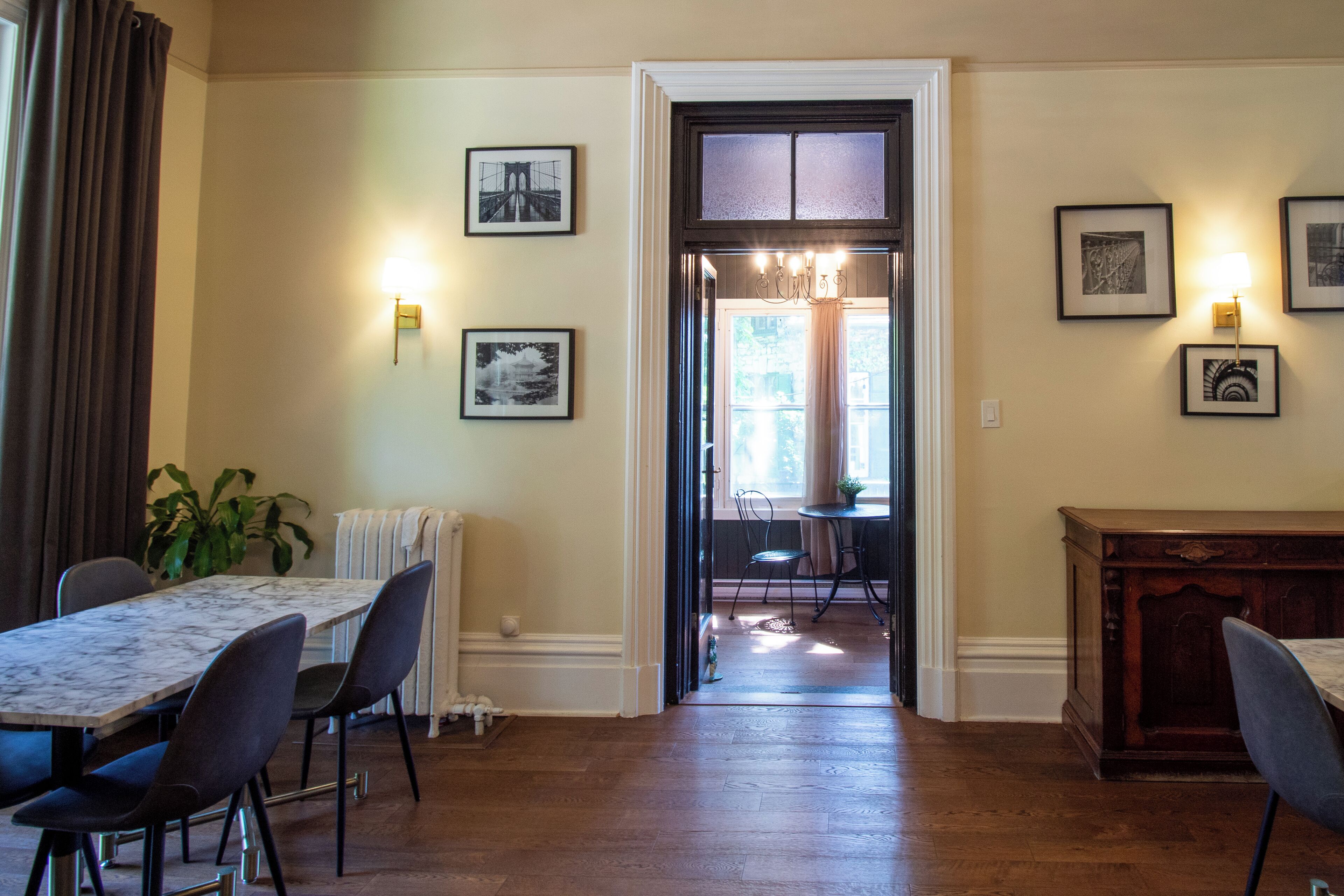 A dining area with a marble table, chairs, and a view through an open doorway to a dining room.