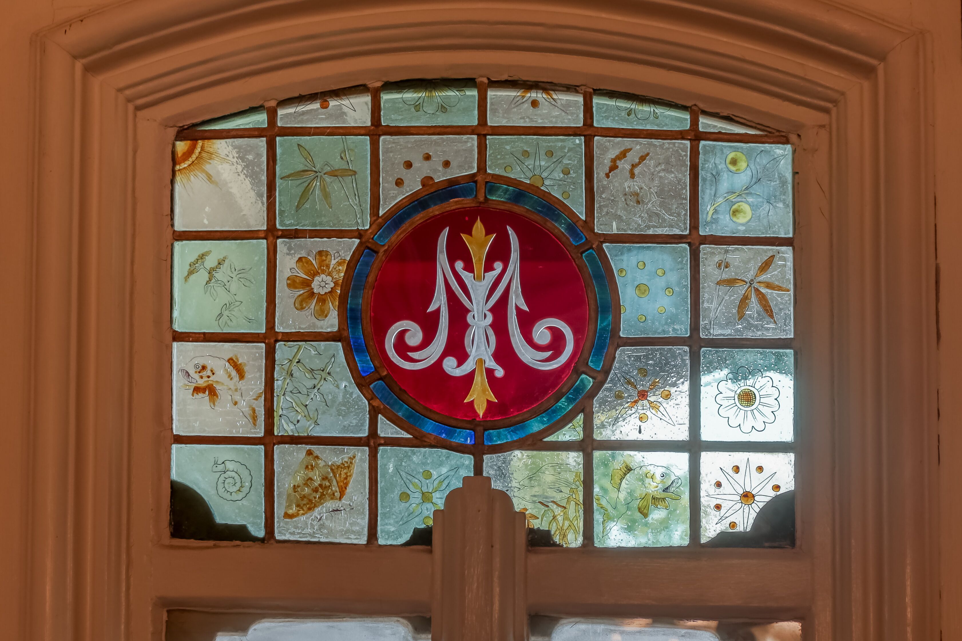 Et farvet glasvindue med et centralt emblem.