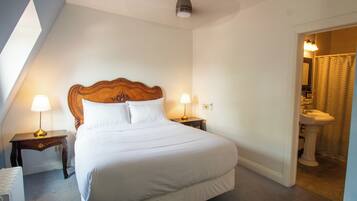 A neatly made bed with white linens, two bedside lamps, and a wooden headboard.