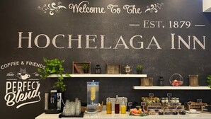 L’espace d’accueil de l’hôtel Hochhelga, avec un panneau d’accueil, un coin café et divers équipements.