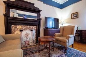 A living room with a fireplace, a television, a sofa, and a chair.