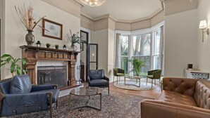 Un salon doté d’une cheminée, de canapés en cuir, d’une table basse et d’une grande fenêtre.