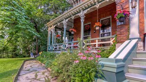 Un bâtiment en briques doté d’un porche, d’un chemin en pierre et de jardinières suspendues.