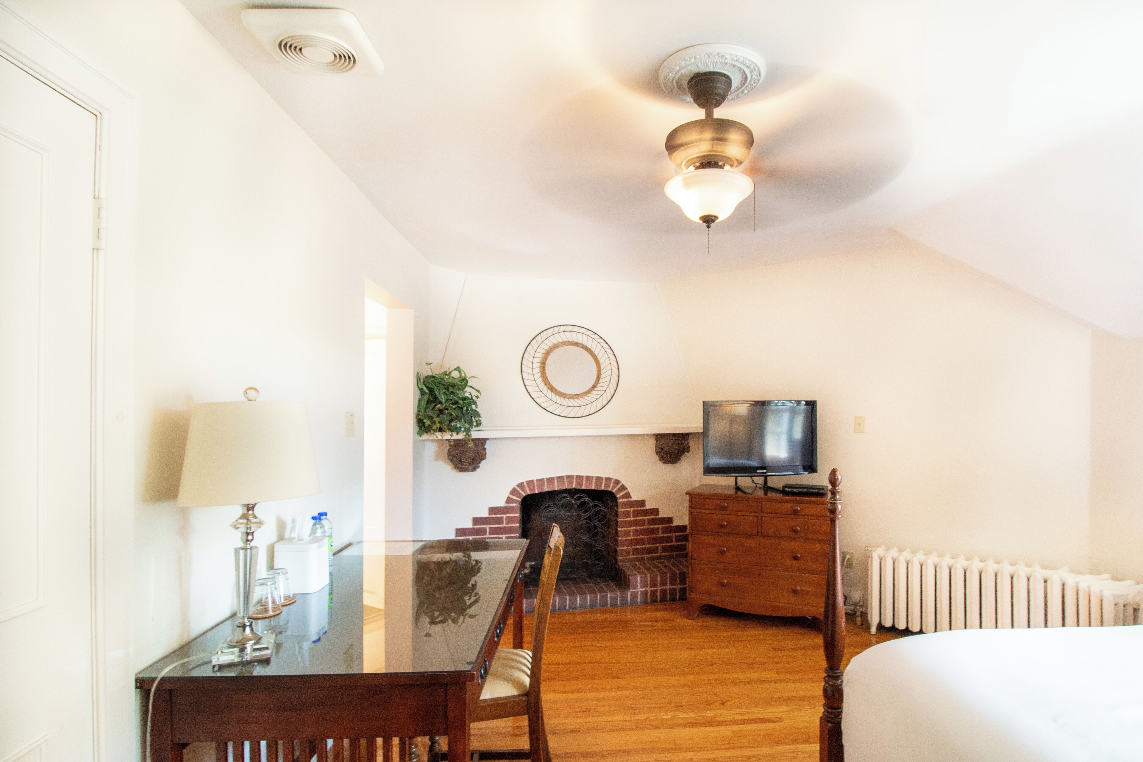 A hotel room with a dining table, chairs, a TV, a fireplace, and a bed.