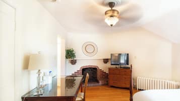 A hotel room with a dining table, chairs, a TV, a fireplace, and a bed.