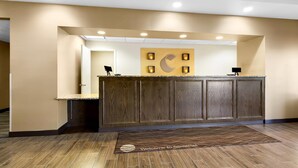 A reception desk with a wooden finish, a wall-mounted phone, and a welcome mat. - Comfort Inn Somerset (Somerset)