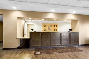 A reception desk with a wooden finish, a wall-mounted phone, and a welcome mat. - Comfort Inn Somerset (Somerset)
