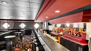 A bar area with a long counter, multiple seating options, and a variety of bottles on display. - Comfort Inn Somerset (Somerset)