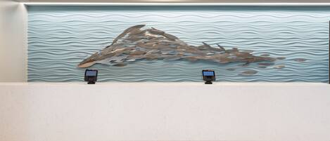 A reception desk with a wavy textured wall behind it.