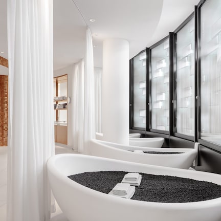 A modern bathroom with a large bathtub filled with black pebbles, white walls, and a tiled floor.