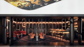 A modern bar area with a bar counter, seating, and a mural on the ceiling.