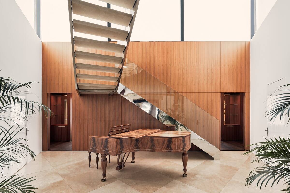 A modern interior with a spiral staircase, wooden panel walls, a round wooden table, and potted plants.