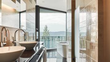 A modern bathroom with two sinks, a bathtub, and a large window offering a view of a balcony.