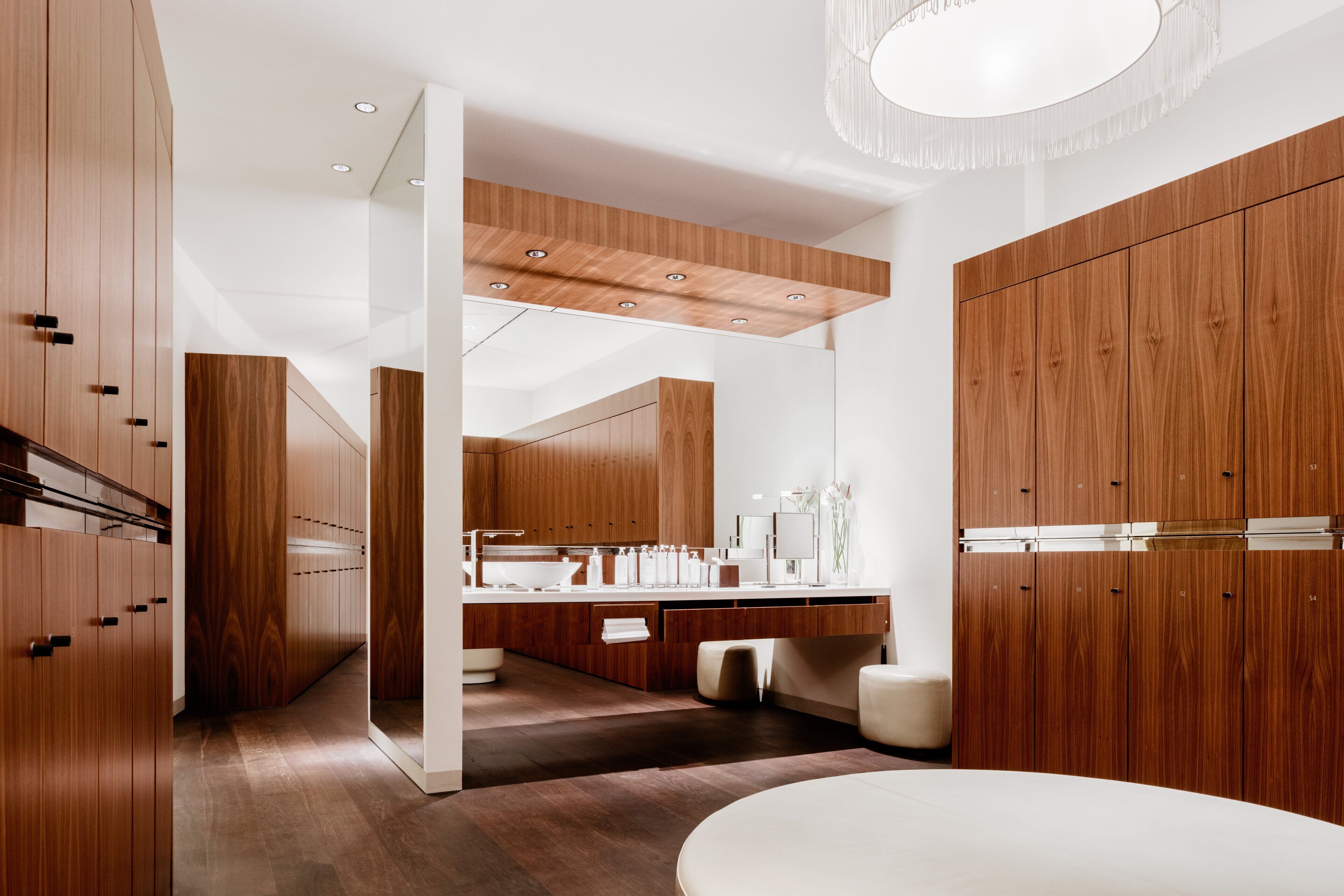 Un baño moderno con muebles de madera, un espejo grande y un lavabo redondo.
