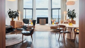 Una sala de estar moderna con un ventanal grande, una chimenea y una zona de comedor con una mesa redonda y sillas.