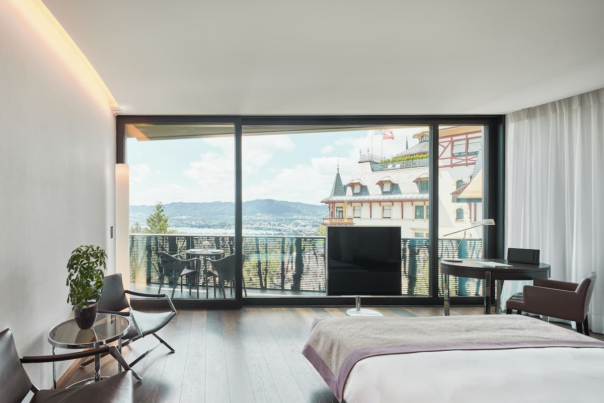 A hotel room with a large window, a bed, a desk, and a chair.