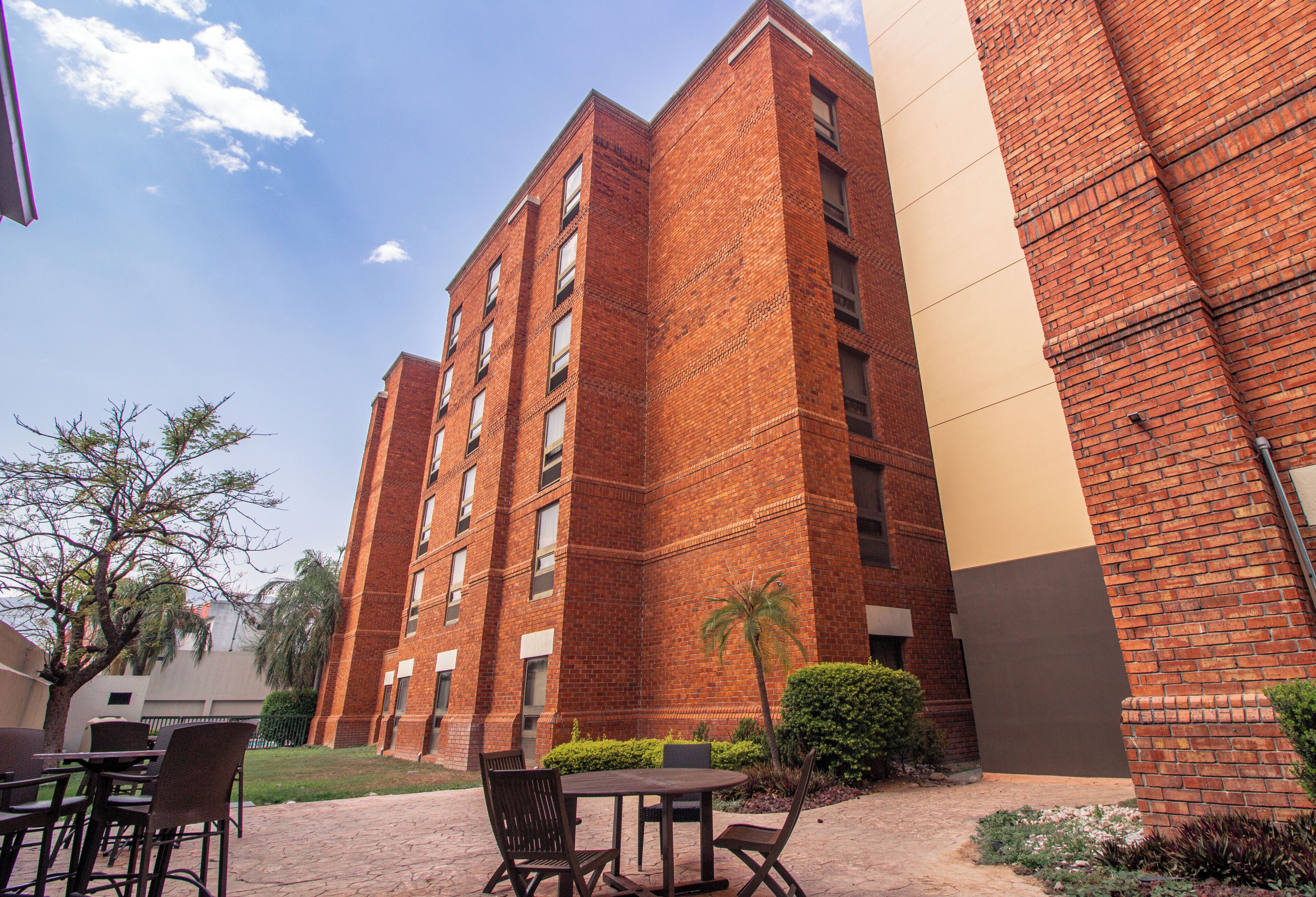 A multi-story brick building with a courtyard featuring outdoor seating and landscaping.