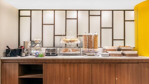 A buffet setup with various food items, a coffee machine, and condiment dispensers. - Wyndham Garden Monterrey Norte (San Nicolas de los Garza)