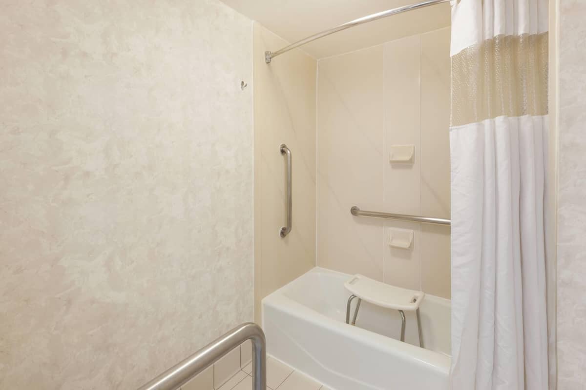 Un baño con bañera, zona de ducha y barandilla.