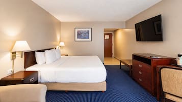 Habitación de hotel con cama, escritorio, silla, televisión e imagen en la pared.