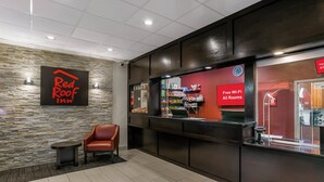 Um saguão do Red Roof Inn, com um balcão de atendimento, área de estar e um relógio.