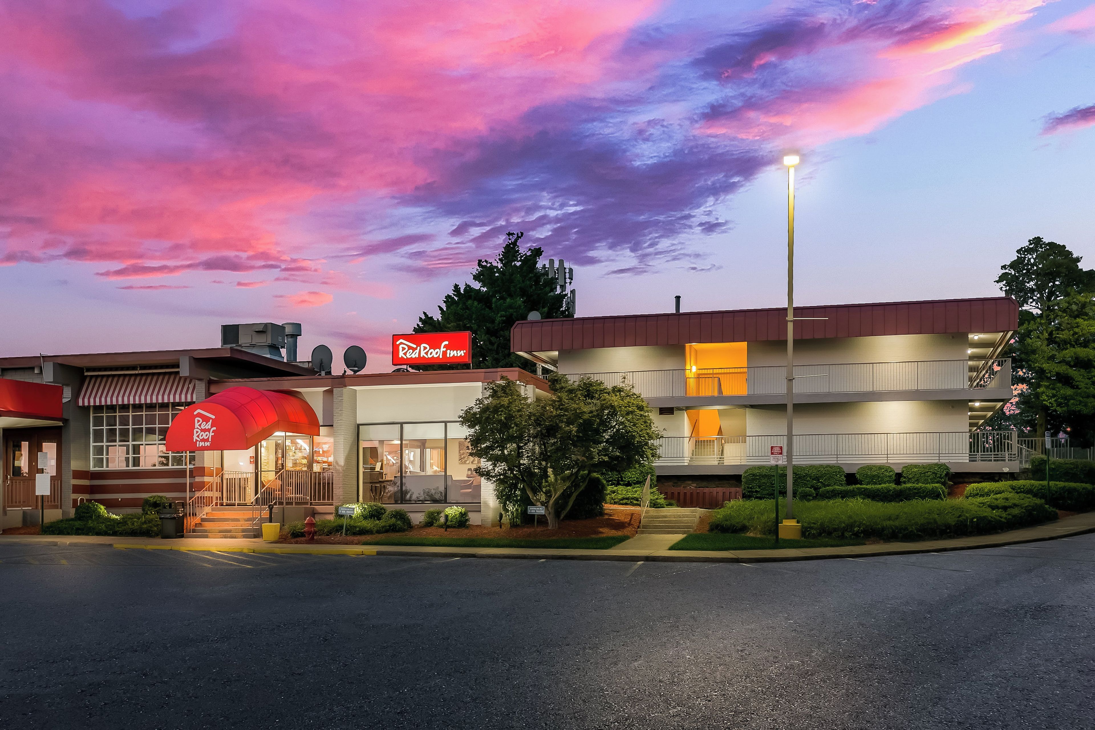 A Red Roof Inn with a modern design, featuring a large entrance canopy and a well-maintained outdoor area.