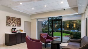 A modern interior with a reception desk, seating area, and large windows offering a view of the outdoors. - Red Roof Inn Baltimore (Baltimore)
