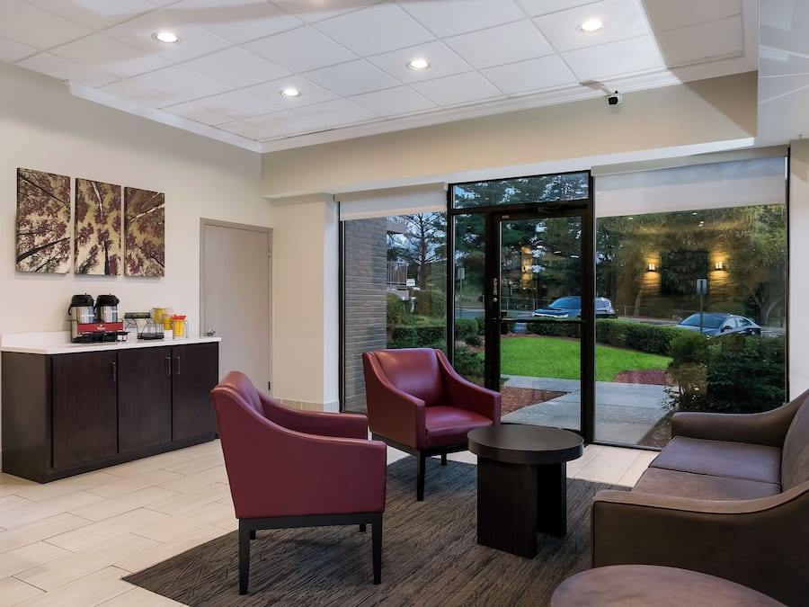 A modern interior with a reception desk, seating area, and large windows offering a view of the outdoors.