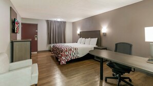 A hotel room with a bed, a desk, a chair, a television, and a window. - Red Roof Inn Baltimore (Baltimore)