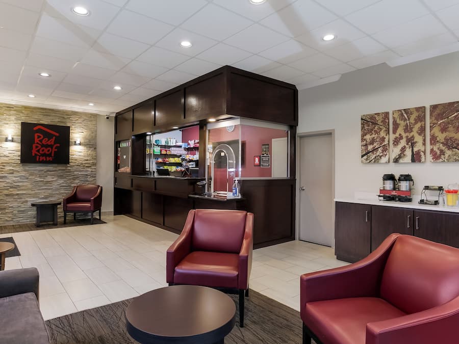 Un vestíbulo de Red Roof Inn con asientos de cuero, una recepción y una estación de café.