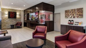 Lobby do Red Roof Inn com cadeiras de couro, um espaço para café e uma parede de pedra.