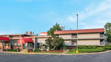 A Red Roof Inn with a red awning, a parking lot, and a building with a red roof.