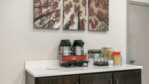 A coffee station with two coffee makers, a water dispenser, and a coffee mug on a counter. - Red Roof Inn Baltimore (Baltimore)