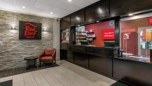 A Red Roof Inn reception area with a stone wall, a leather chair, and a counter with amenities. - Red Roof Inn Baltimore (Baltimore)