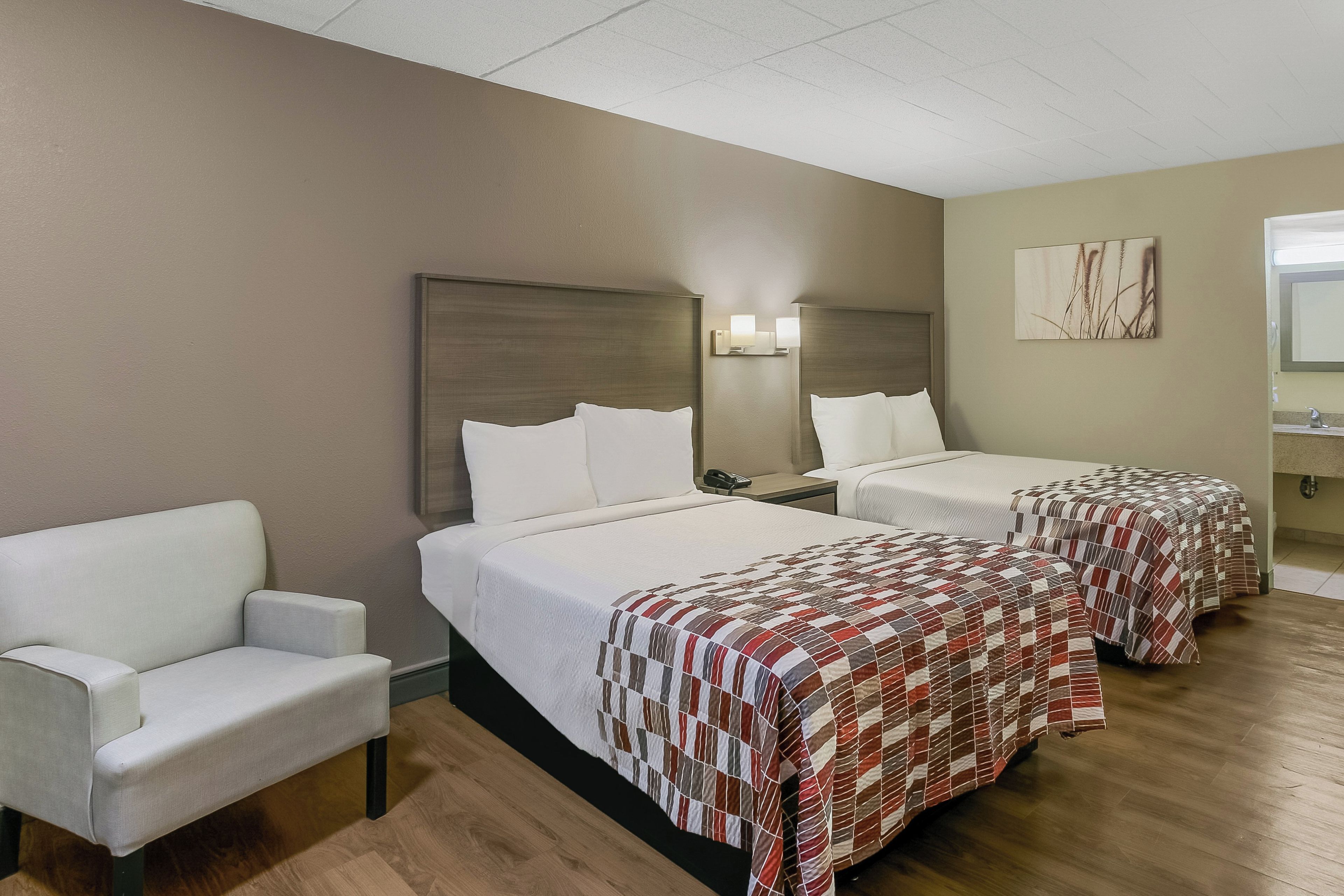 Een hotelkamer met twee bedden, een slaapbank, een nachtkastje en een schilderij aan de muur.