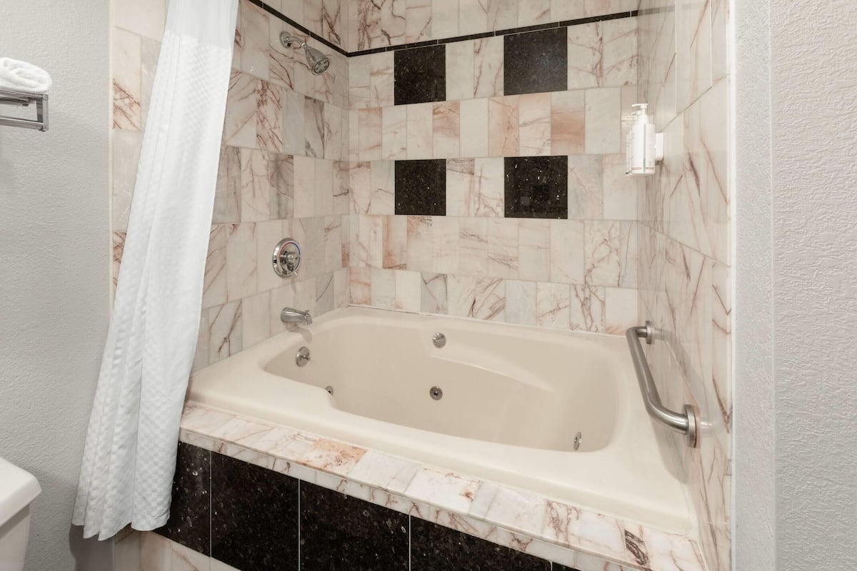 Een badkamer met een bad, douche en toilet.