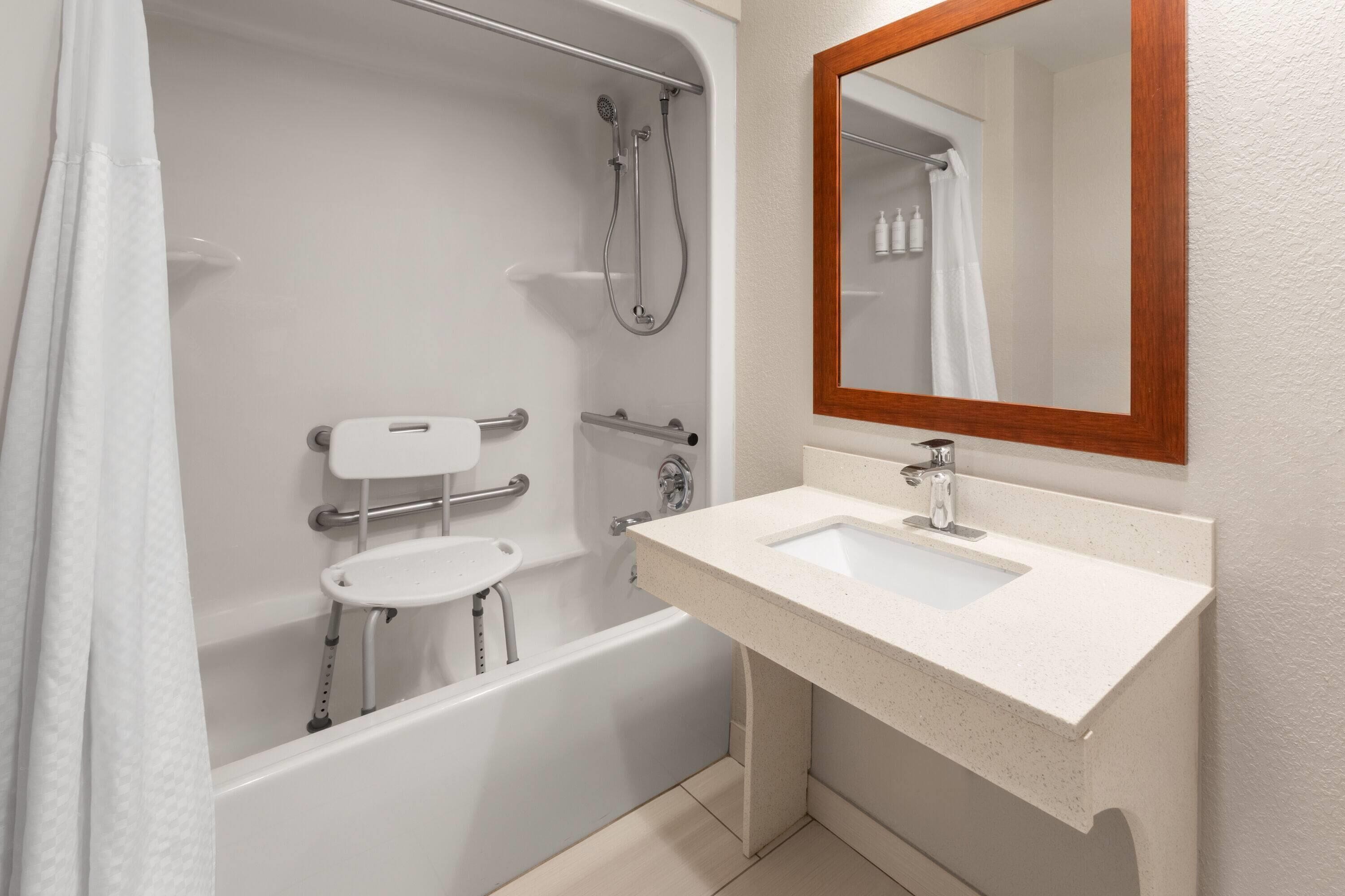 A modern bathroom with a bathtub, shower, and sink.