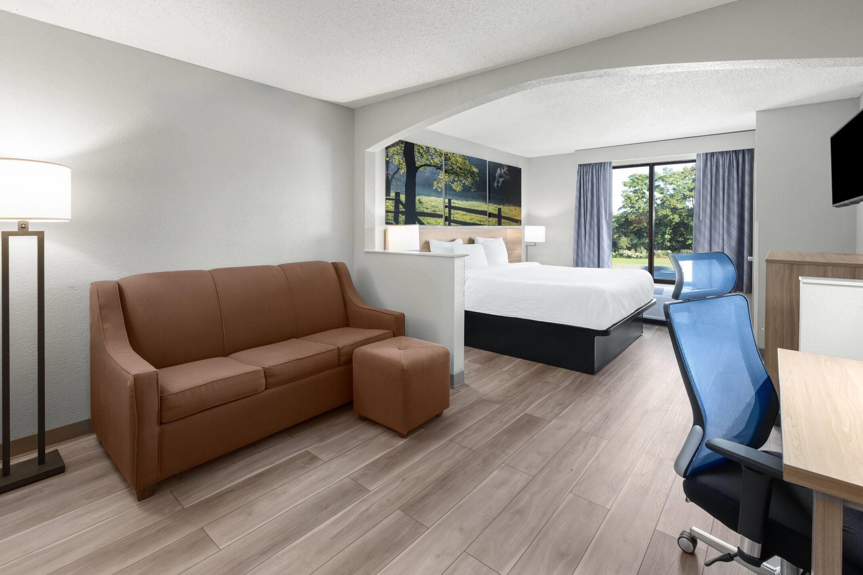 A hotel room with a bed, a sofa, a desk, and a chair.
