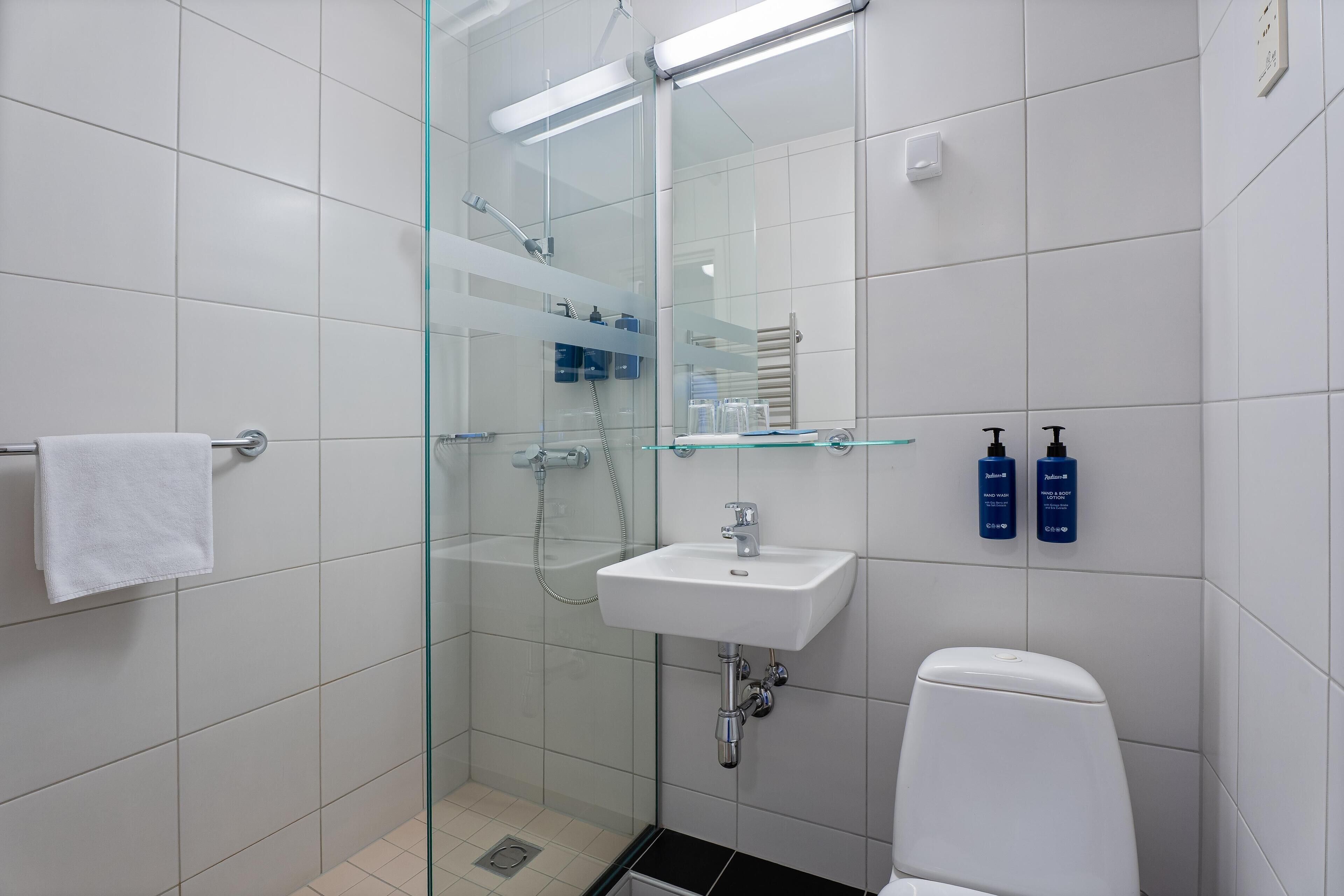 Un baño moderno con ducha envuelta en vidrio, un lavabo blanco y un inodoro.