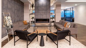 A modern lounge area with sofas, a coffee table, and a fireplace. - DoubleTree by Hilton Denver Cherry Creek (Denver)
