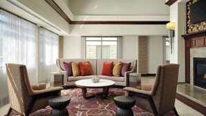 A spacious living room with a sofa set, two armchairs, a coffee table, and a fireplace.